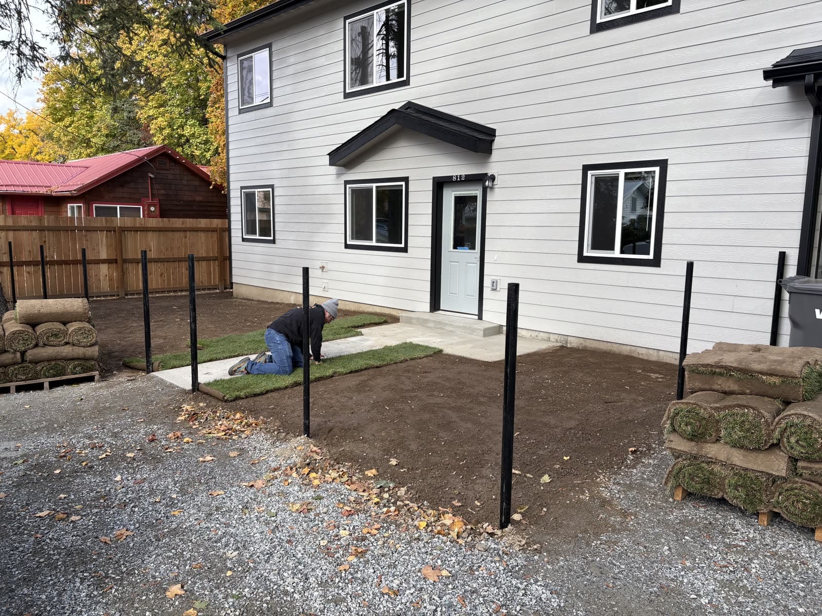 Before: A new install at a white two-story home going from prepped soil to fresh-laid sod.