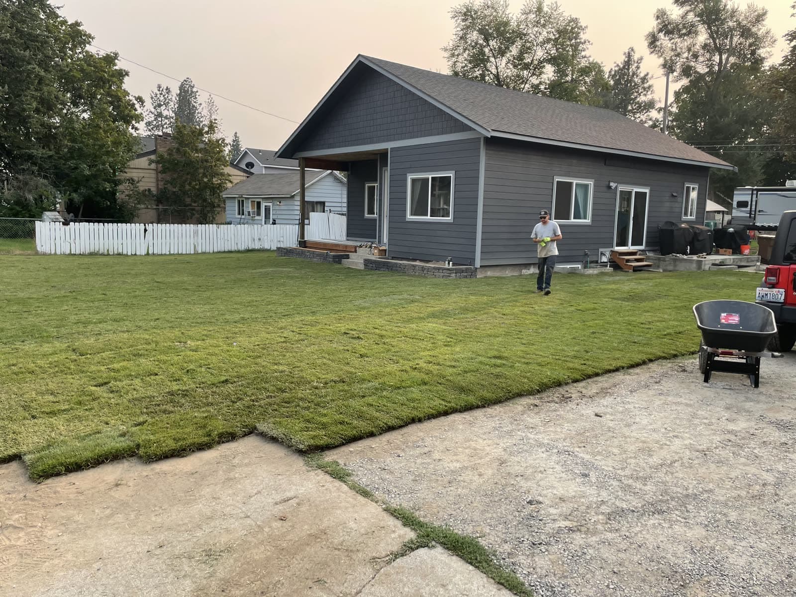 After: A Spokane yard going from bare dirt with fresh-cut sod rolls delivered to a finished green lawn.